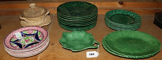 A collection of greenware plates and dishes, other pottery plates and a caneware tub, cover and stand